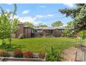 Spacious backyard with lush lawn, patio area, brick fireplace, and mature trees at 5455 E Iowa Ave, Denver, CO 80222