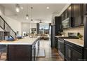 Open-concept kitchen features dark cabinets, stainless steel appliances, and a large island flowing into the living area at 5188 Ward Rd, Wheat Ridge, CO 80033