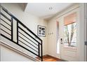 A bright foyer with wood floors, modern railing, and a glass-paneled front door welcomes natural light at 907 E 22Nd Ave, Denver, CO 80205