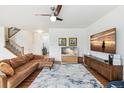 Open living room featuring hardwood floors, large-screen TV, and staircase leading to the second floor at 24356 E Powers Ave, Aurora, CO 80016