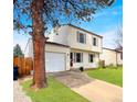 Inviting two-story home with attached garage, set amidst a lush green lawn and mature tree at 10781 Moore St, Westminster, CO 80021