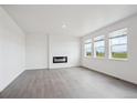Bright living room featuring hard wood floors, a fireplace, and three windows bringing in natural light at 4115 Marble Dr, Mead, CO 80504