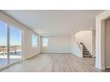 Bright open living room with wood-look flooring, staircase and sliding glass door at 14115 Bunny Hop Ln, Parker, CO 80134