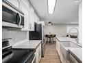 Stylish kitchen featuring herringbone backsplash, stainless appliances, and a farmhouse sink at 230 E Highline Cir # 101, Centennial, CO 80122