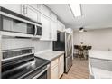 Galley kitchen featuring white cabinets, stainless appliances, and a dining area at 230 E Highline Cir # 101, Centennial, CO 80122