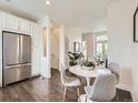 Bright dining area with stainless steel fridge, white cabinets, and hardwood floors at 2507 Moline St, Aurora, CO 80010