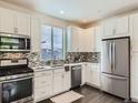 Well-lit kitchen showcases modern appliances and white cabinetry with a stylish backsplash at 2507 Moline St, Aurora, CO 80010