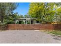 Home featuring a well-maintained lawn and mature trees, and a wooden fence and gravel driveway at 3209 E Yale Way, Denver, CO 80210