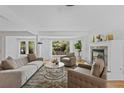 Bright living room with white walls, fireplace, plush seating, large windows offering views of the well landscaped exterior at 3209 E Yale Way, Denver, CO 80210