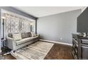 Cozy living room featuring a stylish sofa, hardwood floors, and ample natural light at 4222 S Himalaya Way, Aurora, CO 80013