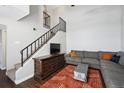 Cozy living room with dark wood floors, comfortable seating, and staircase at 7705 W 87Th Dr, Arvada, CO 80005