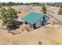 Aerial view of a barn with a green metal roof and a fenced enclosure on a rural property at 12160 Spring Creek Rd, Parker, CO 80138