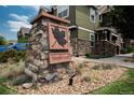 Stone sign with a maple leaf emblem marking the community entrance at 7090 Simms St # 202, Arvada, CO 80004