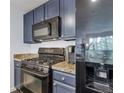 Close up of kitchen area with black appliances, granite counters and blue cabinets at 1441 Central St # 209, Denver, CO 80211