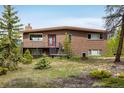 Charming brick home with a well-maintained lawn, front porch, and mature trees creating a peaceful setting at 401 Highway 72, Golden, CO 80403