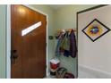 Home entryway with wood door, coat rack, decorative art and adjacent hallway at 3317 W Belmont Ave, Littleton, CO 80123