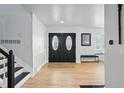 Bright foyer featuring hardwood floors, double front doors, staircase, and bench seating near a bay window at 6787 E Exposition Ave, Denver, CO 80224
