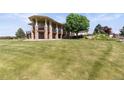 Lush backyard showcasing the home's veranda with stone pillars and expansive green lawn at 3358 Castle Butte Dr, Castle Rock, CO 80109