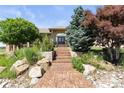 Inviting home entrance featuring a decorative walkway, stone accents, and lush landscaping at 3358 Castle Butte Dr, Castle Rock, CO 80109