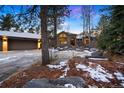 Two-story home with a three car garage and a manicured yard with large rocks and trees at 29432 Camelback Ln, Evergreen, CO 80439