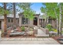 Charming home with a bridge entrance, beautiful landscaping, and mature trees at 29432 Camelback Ln, Evergreen, CO 80439