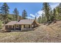 Rear view of the rustic cabin, surrounded by trees and natural landscape at 30570 Highway 72, Golden, CO 80403