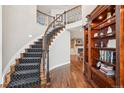 Grand foyer with a curved staircase, hardwood floors, wrought iron railing, and a built-in bookshelf at 16342 Parkside Dr, Parker, CO 80134
