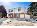 Inviting two-story home featuring a brick and siding facade, complemented by a front porch and a driveway amid winter snow at 11821 Joplin Ct, Commerce City, CO 80022