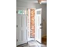 Bright entryway with a white front door, brick accent wall, and tile flooring at 4753 S Gar Way, Littleton, CO 80123