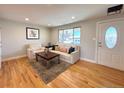 Bright living area with hardwood floors, neutral decor, a large window, and a stylish front door at 6556 Wolff St, Arvada, CO 80003