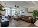 Bright living room featuring a stylish leather sofa, modern decor, and ample natural light from large windows at 16382 E 111Th Dr, Commerce City, CO 80022