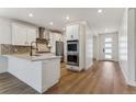Open concept kitchen features stainless steel appliances, an island, white cabinets, and hardwood flooring at 42982 Colonial Trl, Elizabeth, CO 80107