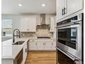 Modern kitchen features white cabinets, quartz countertops, stainless steel appliances and a herringbone backsplash at 42982 Colonial Trl, Elizabeth, CO 80107