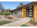 Modern home entrance boasting wood elements, sleek black accents, and stylish landscaping features at 4 Meadowlark Ln, Littleton, CO 80123