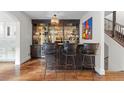 Stylish bar area features dark cabinetry, glass shelving, and seating for three at 579 Madison St, Denver, CO 80206