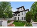Elegant white home with tile roof, black trim, arched porch, balcony and professionally landscaped lawn at 579 Madison St, Denver, CO 80206