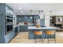 Bright eat-in kitchen boasts gray cabinets, stainless appliances, an island with counter seating, and pendant lighting at 7120 S Sheridan Ct, Littleton, CO 80128