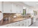Well-lit kitchen boasts elegant white cabinetry, mosaic backsplash, and stainless steel appliances at 591 Nome St, Aurora, CO 80010