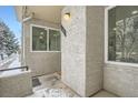 Side view of a townhome entrance with snowy landscaping at 1825 Kendall St # 101, Lakewood, CO 80214