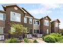 Charming townhome with brick accents, a quaint entryway, and lush green landscaping at 15546 W 64Th Loop # C, Arvada, CO 80007