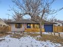 A cute single-story home boasts a blue door, matching garage, and wood accents, radiating curb appeal at 1140 S Elm St, Denver, CO 80246