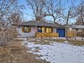 Inviting single-story home with a blue door, natural wood accents, and a well-maintained front yard with mature trees at 1140 S Elm St, Denver, CO 80246