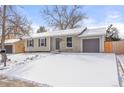 A single-story home with an attached garage, neutral paint, and a spacious driveway dusted with snow at 2023 S Idalia St, Aurora, CO 80013