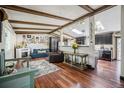 Inviting living room with hardwood floors, wooden ceiling beams, fireplace, and a glimpse into the modern kitchen at 12175 W 68Th Pl, Arvada, CO 80004