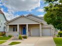 Well-maintained single-story home with a blue front door, covered porch, and a two-car garage at 1688 Aquamarine Dr, Brighton, CO 80603