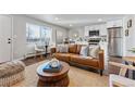 Comfortable living room showcasing a leather sofa, area rug, and a modern kitchen with stainless steel appliances at 1275 Winona Ct # B, Denver, CO 80204