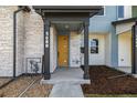 Close-up of a townhome's welcoming yellow front door, framed by stone and a covered porch at 5688 N Killarney Ct, Aurora, CO 80019