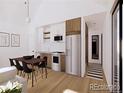 Bright, open-concept kitchen and dining area with sleek white cabinets, stainless steel appliances, and modern dining set at 769 Turner St, Erie, CO 80516