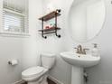 Cozy half bathroom with modern fixtures, pedestal sink, and stylish wood shelving at 17470 E 95Th Pl, Commerce City, CO 80022