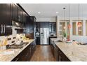 Stunning kitchen with stainless steel appliances, sleek black cabinetry, stone counters, and a central island with a sink at 24322 E Mineral Dr, Aurora, CO 80016